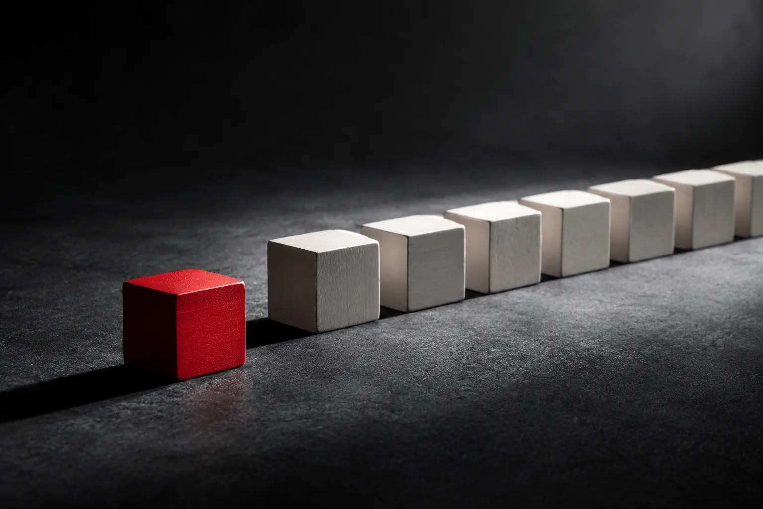 Red cube outside a receding row of pale cubes on a dark textured surface.