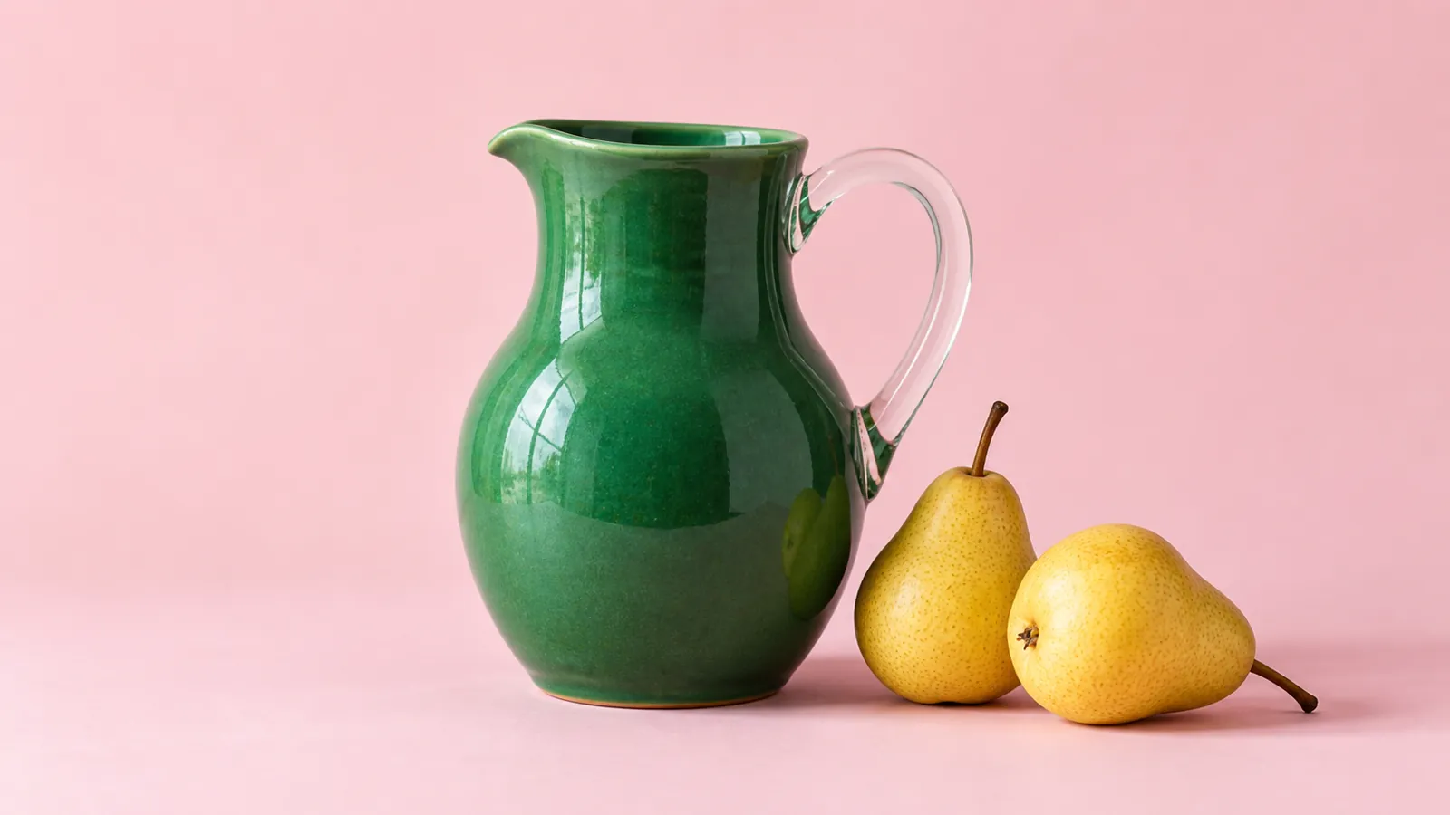 Illustrative green ceramic jug and yellow pears against a pale pink background