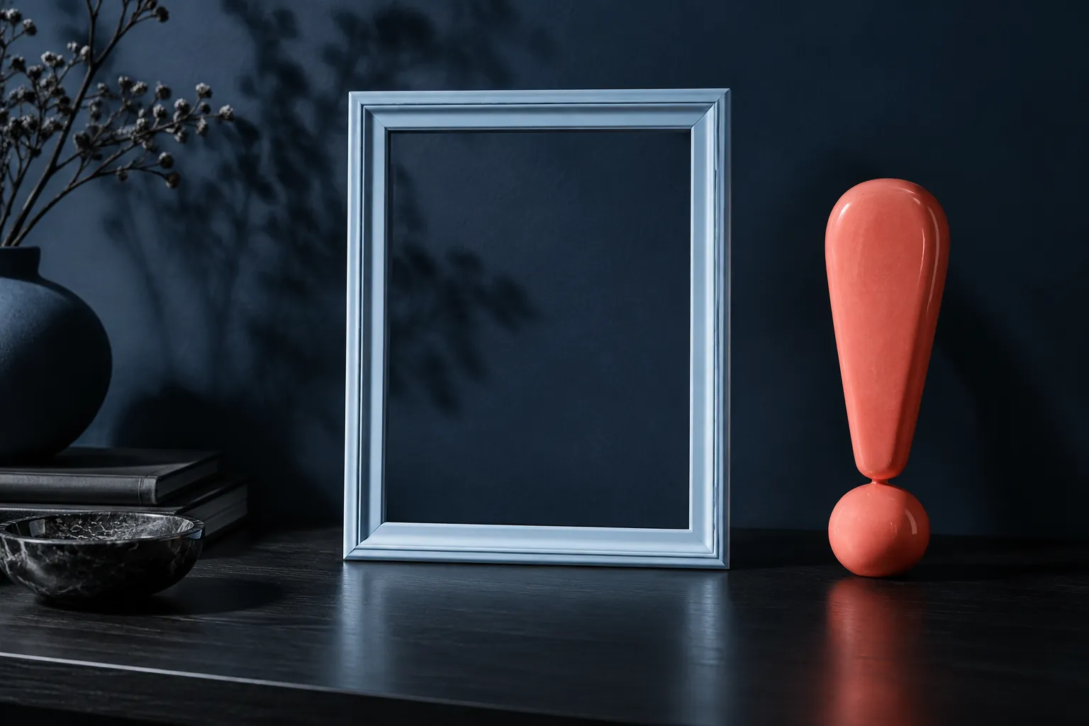 Empty silver-blue frame and coral exclamation sculpture against navy wall