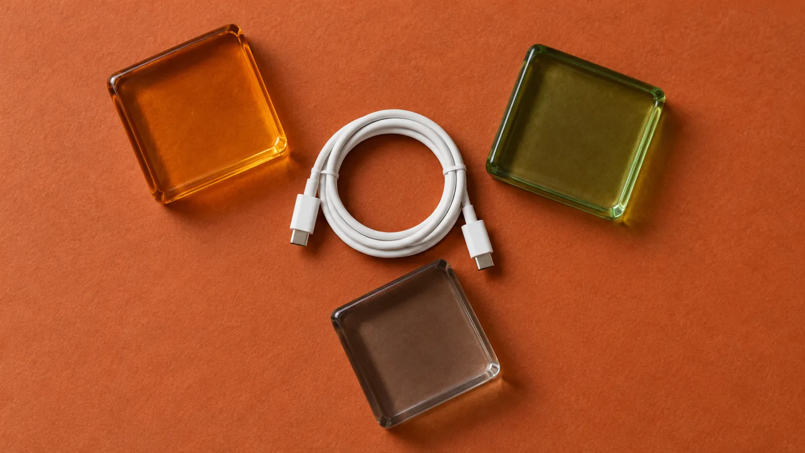 Conceptual glass tiles and a coiled white cable on an orange surface
